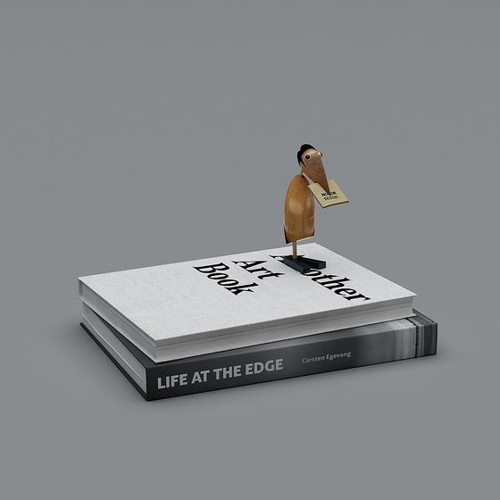 Stack of two art books with wooden bird figure on grey background
