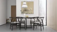 Dining room with black round table wooden chairs white ceiling lights and bird wall painting