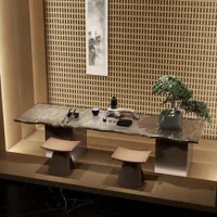 Modern tea room featuring long wood table, two stools, bonsai tree, and decorative wall panel