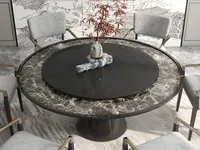 Round marble dining table with a black center piece and grey chairs on a rug