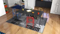 Modern interior design showing black dining table and colorful chairs on a large patterned rug