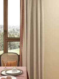 Close up of dining table with plate, glass, chair with striped pillow, and beige curtains