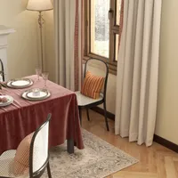 Traditional dining room with pink tablecloth wooden chairs patterned rug window curtains fireplace and lamp