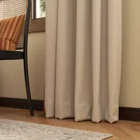 Close up of beige curtain fabric on wooden floor with rug and a woven chair