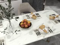 Close up of white dining table with plates, yellow napkins, wine glasses, and red apples