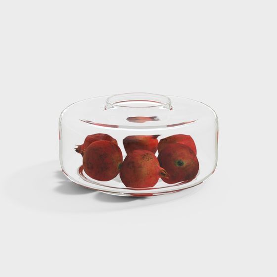 Clear glass bowl with red pomegranates and small handle on white background