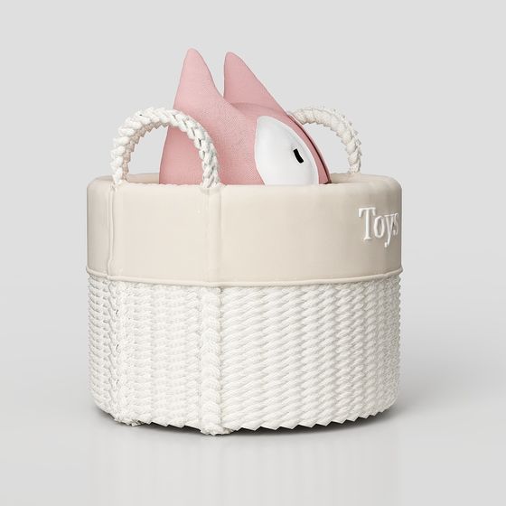 Cream woven storage basket with rope handles and pink toy on grey background