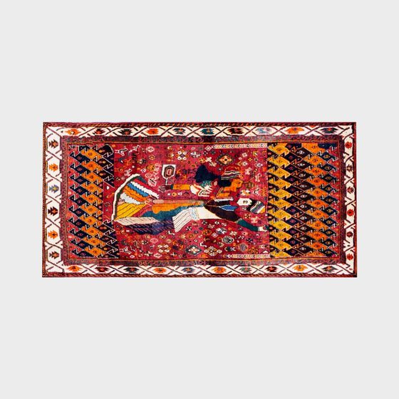 Red vintage rug with colorful tribal figure and geometric patterns on grey background