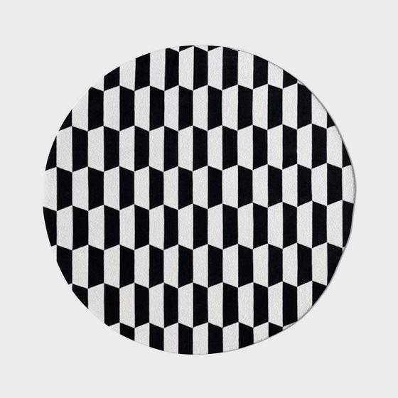 Round rug with black and white geometric pattern on grey background