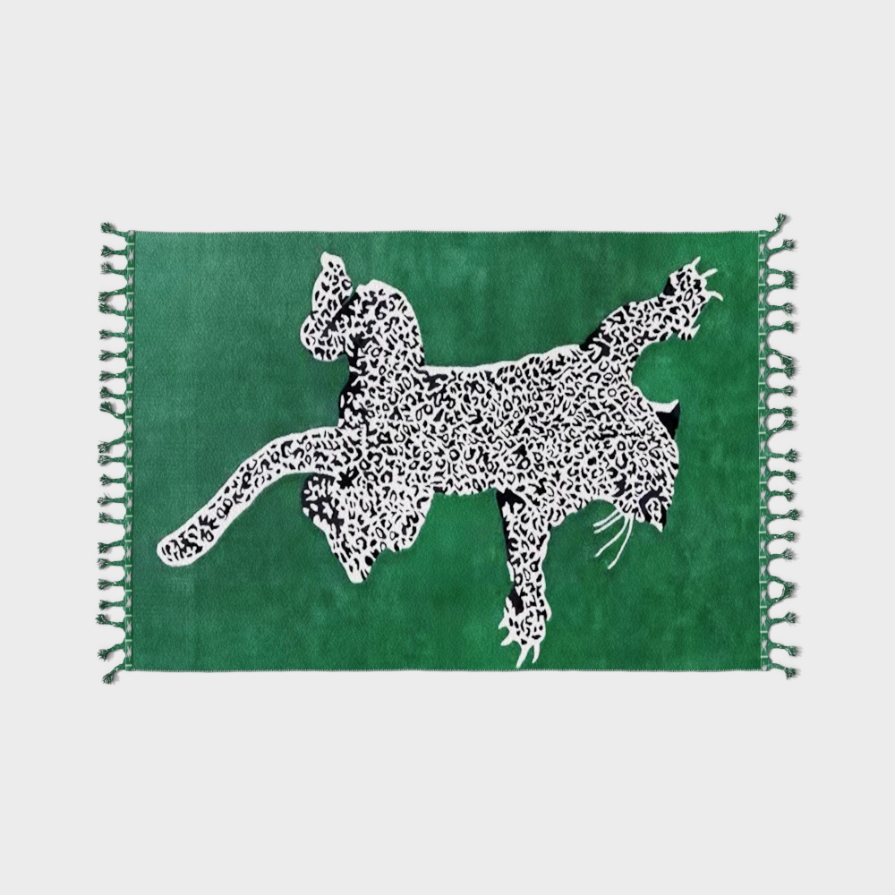 Green rug with white and black leopard pattern and tassels on light grey background