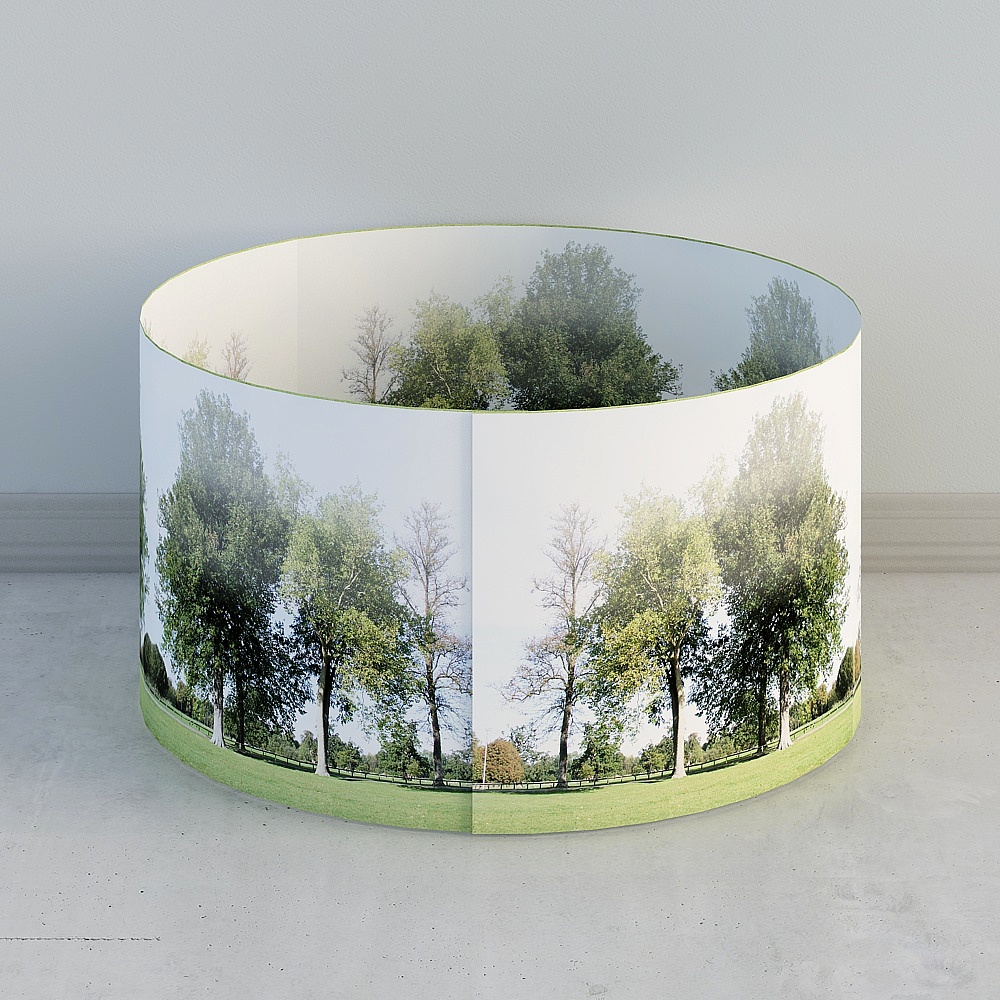 Large round drum shade with green trees and grass landscape print on grey background
