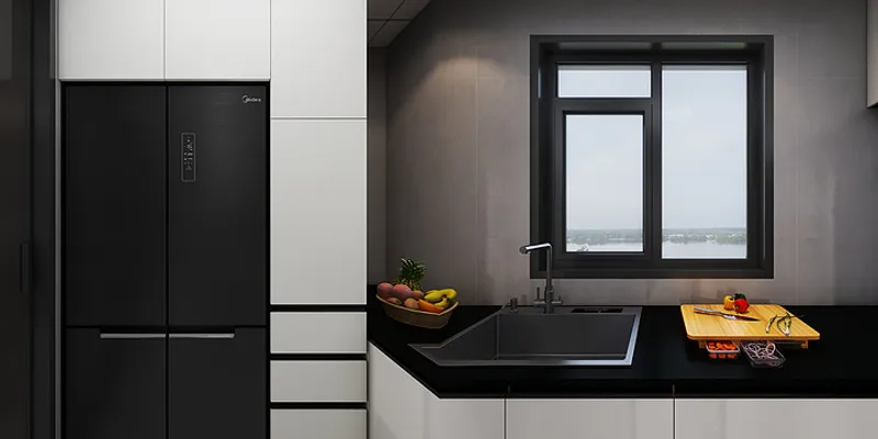 Modern kitchen featuring black refrigerator white cabinets black countertop sink windows and fresh fruit bowl