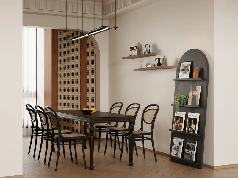 Elegant dining area featuring black table, rattan chairs, wall shelves, book display, and ceiling light