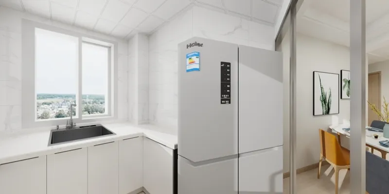 Modern white kitchen with marble wall tiles, grey refrigerator, window view, and black sink area.