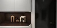 Modern white cabinet with dark wood shelf holding books and decor beside a black door