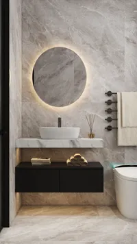 Modern bathroom features round glowing mirror white sink black floating cabinet and marble wall tiles