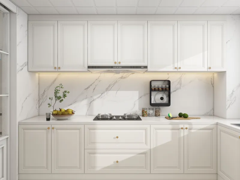 Modern white kitchen with marble wall, white storage cabinets, gas stove, and fresh fruit bowl