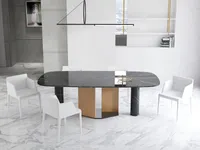 Close view of black marble dining table with wood base surrounded by comfortable white chairs