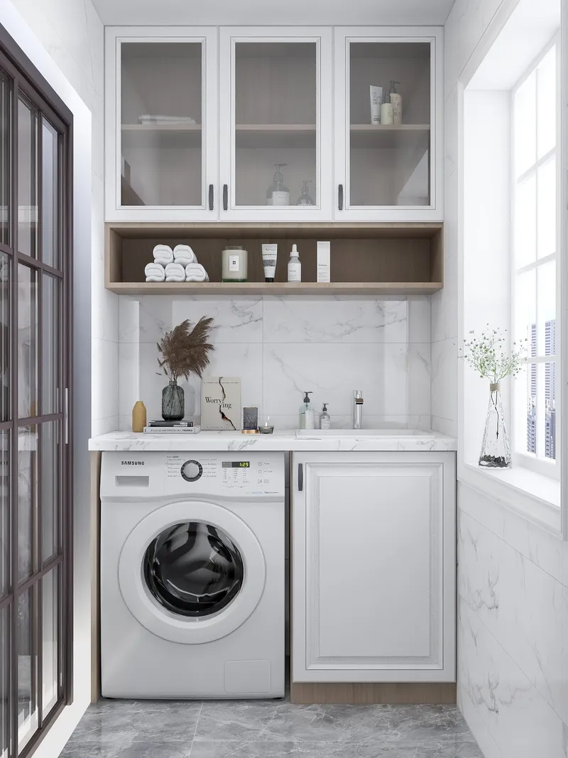 Modern balcony laundry area with white washing machine under marble counter and glass storage cabinets