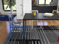 Modern dining room with black table, blue clear chair, grey rug, yellow mug, and books