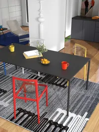 Black dining table with red chair and yellow chair showing books and mugs on top