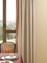 Beige curtain with orange trim next to a window showing green trees and a table