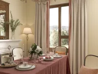 Dining room interior with pink tablecloth white flowers chairs floor lamp fireplace and large windows