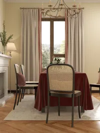 Classic dining room featuring red tablecloth, cane back chairs, ceiling light, fireplace, and window curtains