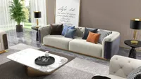 Modern living room with beige sofa, marble coffee table, green plant, and black side tables