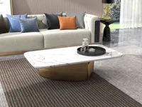 Detail view of a white marble coffee table with gold base on a striped rug