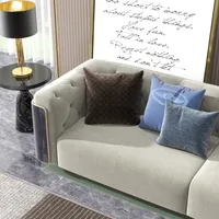 Light beige sofa with blue pillows next to a black side table and gold lamp