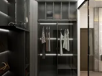 Dark wood walk-in closet featuring glass cabinet doors internal light strips hanging clothes and bags