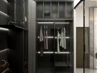 Dark walk in closet with glass doors, internal LED lighting, hanging clothes, and designer handbags.