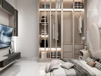 Modern bedroom featuring glass wardrobe with lights wall mounted television and bed with soft pillows