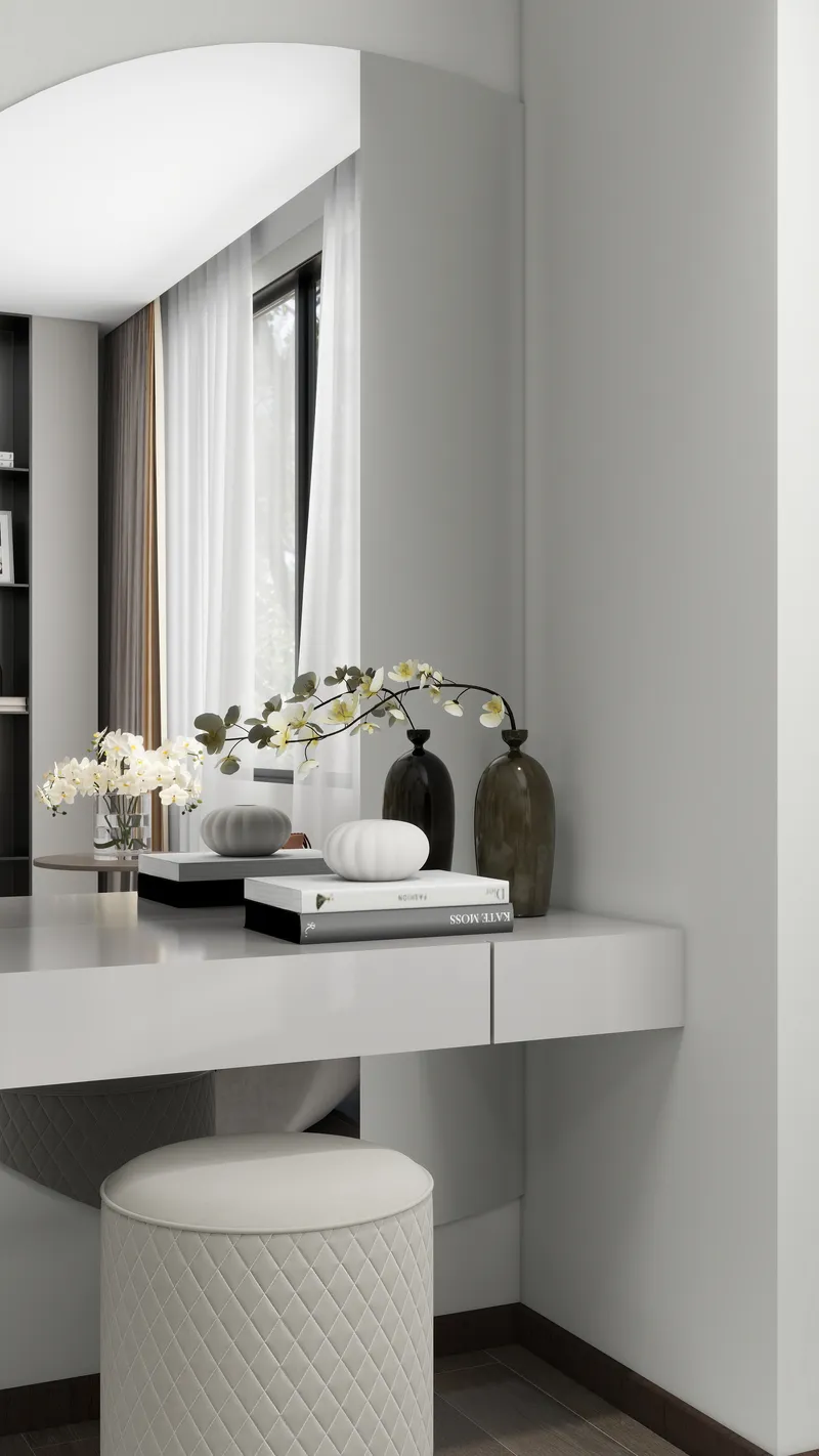 White dressing table with round mirror featuring books vases flowers and a grey round footrest