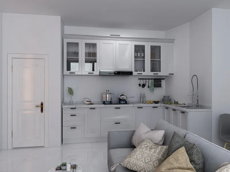 White kitchen cabinets with marble top next to grey sofa with pillows and white door