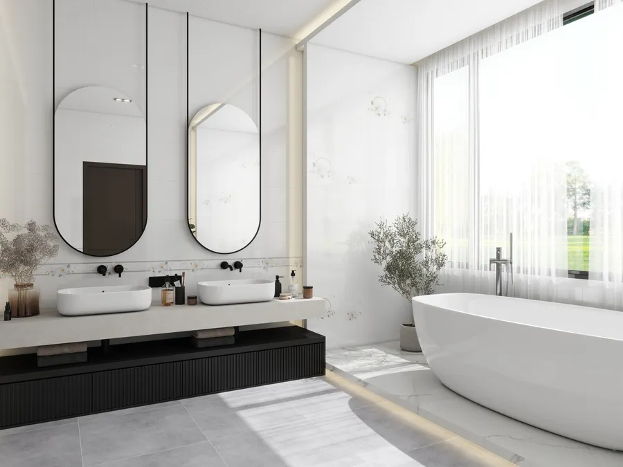 Bright modern bathroom with two white sinks, oval mirrors, large bathtub, window, and marble tiles