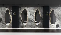 Grey marble wall with black wall panel backlit mirrors and golden round wall light fixtures