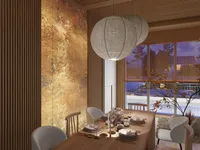 Wooden dining table with white chairs under round ceiling lights with a textured wall panel