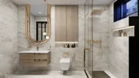 Modern bathroom with marble tiles, wooden cabinet, gold mirror, white toilet, and glass shower enclosure