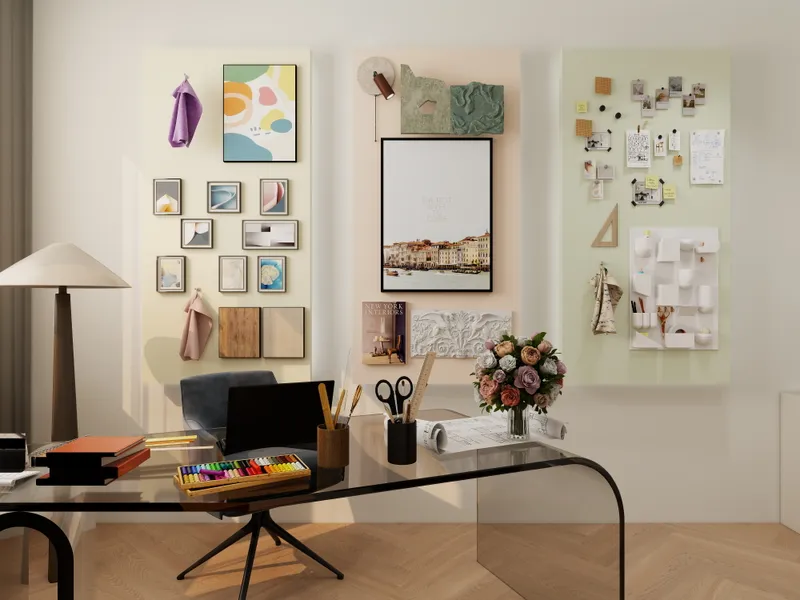 Modern workspace featuring glass desk, black chair, wall mood boards, art supplies, and fresh flowers