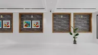 Modern white wall with four wooden frames, dark brick backings, abstract art, and green plant