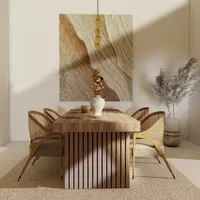 Wooden dining table with woven chairs under a ceiling light with large abstract wall painting