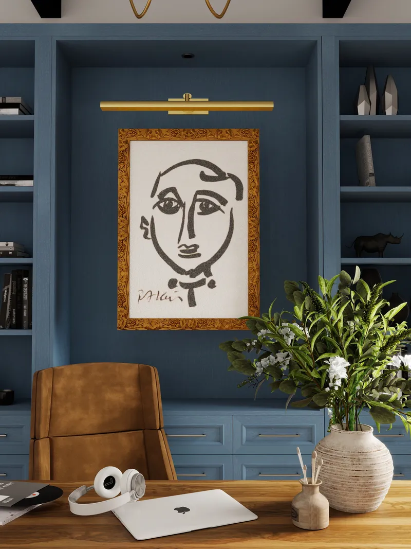 Home office with blue cabinets, framed art, wall light, brown leather chair, and wooden desk